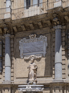 An architectural detail shot of the Baroque Kalsa facade at Quattro Canti in Palermo, Sicily, featuring a monumental Latin inscription dedicated to King Philip III above a marble allegorical fountain.