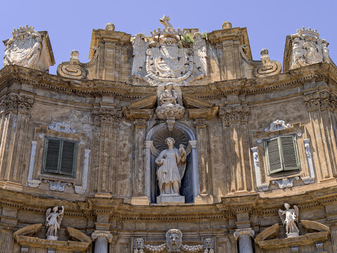 Architectural view of the upper tier of the Kalsa facade at Quattro Canti in Palermo, Sicily, featuring the marble statue of Saint Agatha beneath a grand royal coat of arms.