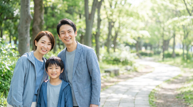 新緑の公園で微笑む父母と小学生の息子