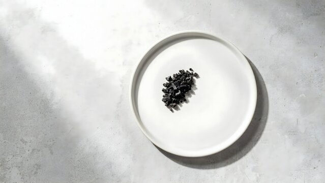Black Cumin Seeds on White Round Plate with Light Gray Background