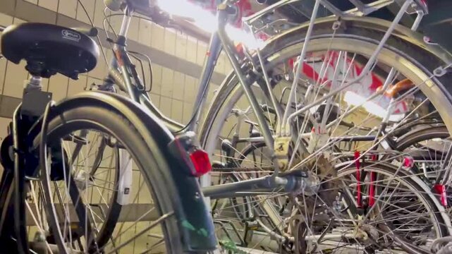 Horizontal panning shot from left to right across a dense indoor bicycle parking lot with rows of parked city bikes