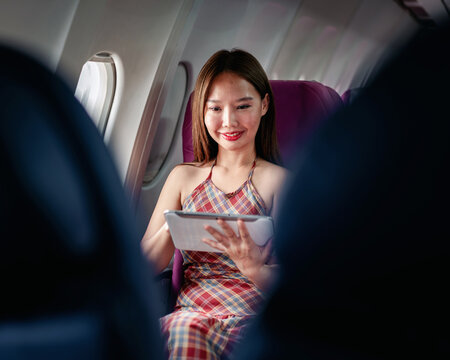 woman traveler passenger flying airplane seat looking digital ta