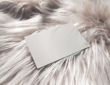 Blank white business card mockup template on soft faux fur fabric