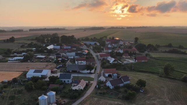 Aerial drone view of rural villages and agricultural fields near Opole and Nysa in Poland, showing geometric farmland patterns, scattered houses, winding country roads and green meadows in daylight.