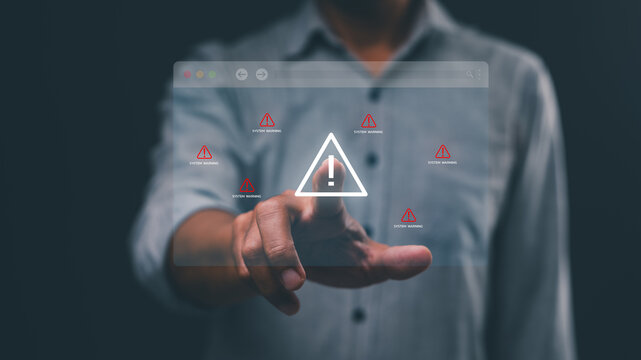 A person interacts with a transparent digital interface displaying multiple warning alerts and an exclamation mark symbol.