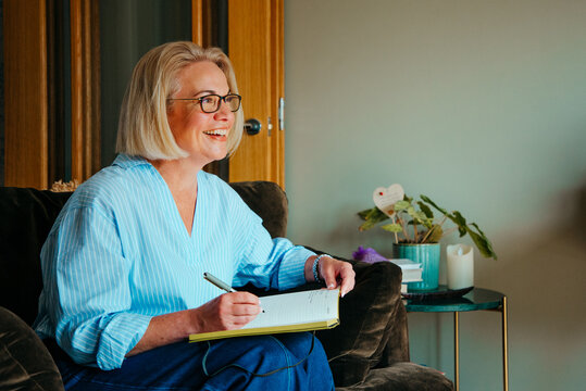 Portrait of smiling middle aged woman writing in a notebook
