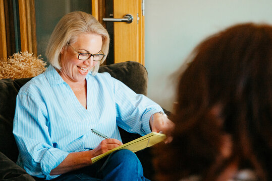 Attractive middle aged woman in conversation and taking notes.