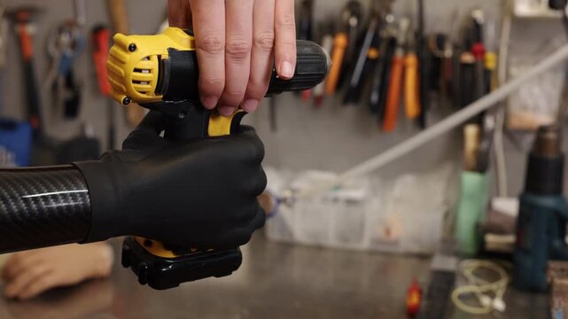 yellow drill, hand prosthesis, adaptive technology. Prosthetic hand securely grips drill, highlighting precision and effectiveness in workshop setting.
