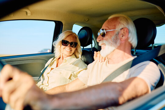 Happy senior couple driving car, smiling and enjoying a summer road trip, celebrating a joyful retirement travel