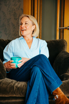 Woman holding a coffee cup conversing with someone off camera
