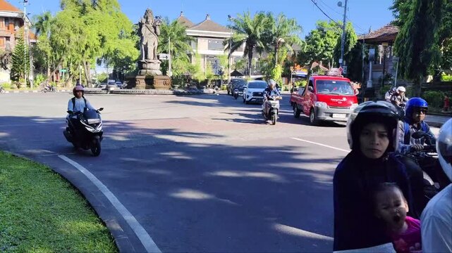 Traffic passing Catur Muka statue fountain landmark in Denpasar city, Bali.