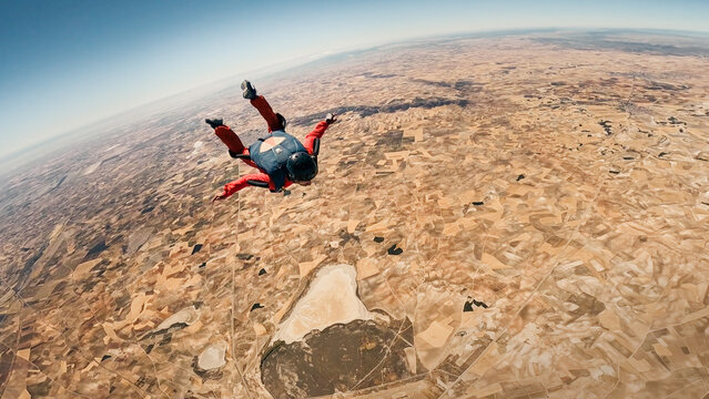 Skydiver in freefall above a vast landscape