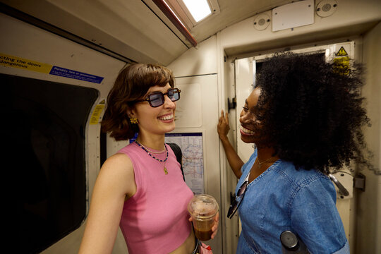 Two casual women chat in a subway train