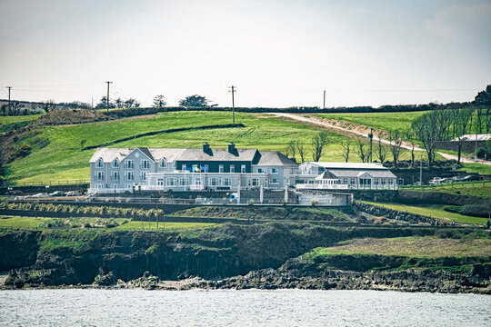 West Cork, Ireland, April 22, 2023. A large building with many windows and is situated on a grassy slope, while a body of water lies in the foreground. Dunmore House Hotel.