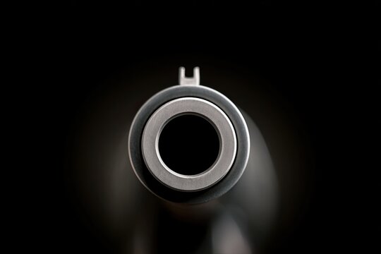 Close-up, head-on view of a gun barrel against a dark background
