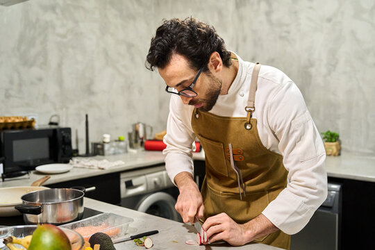 Man wearing apron preparing healthy meal in kitchen