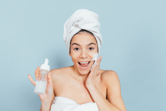 Happy woman uses facial care routine against plain background