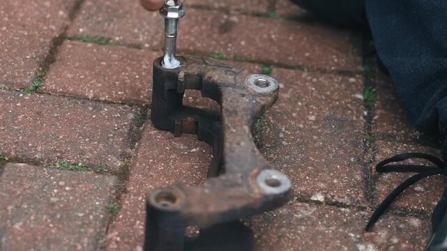 Brake caliper guide pin receiving special lubricant during brake repair process. DIY automotive maintenance preparing caliper bracket for smooth component movement. Close up vehicle servicing focusing