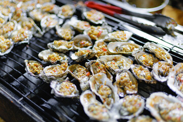 Oysters grilling with toppings on outdoor grill night market Sanya, Hainan Island, China © Parilov