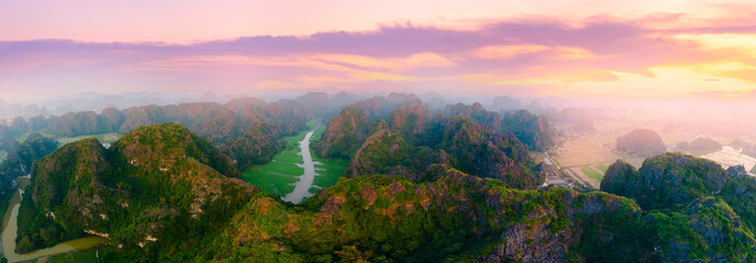 Obraz premium Scenic aerial view panorama of Ninh Binh's lush green limestone mountains at sunset