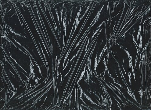 Crumpled plastic overlay texture on a black background. Wrinkled cellophane for grunge cover designs, banners, and backgrounds.