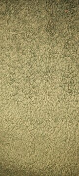 Close-up full frame view of a soft green fleece fabric texture, showing the fuzzy fibers and surface details.
