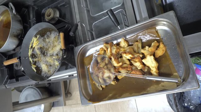 Mixed appetizers cook in bubbling hot oil, creating crispy starters for guests during a festive catered restaurant event.