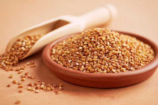 Roasted buckwheat groats wellness flatlay in warm amber gold tones on warm terracotta surface with copy space