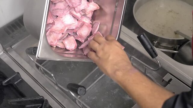 Fresh ravioli are dropped into boiling water as chefs begin preparing handmade Italian pasta for a festive restaurant banquet.