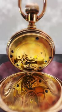 Vertical video social media - Closeup of internal cogs and spring movement of a beautiful, 14 carat, 19th century, antique gold pocket watch, reflected in its own case as the ticking mechanism moves.