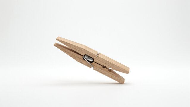 Natural wooden clothespin with a silver spring mechanism on a white background clothes peg