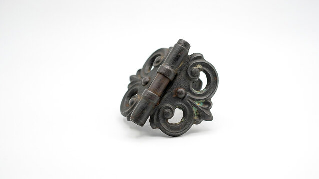 Ornate antique metal hinge with decorative scrollwork and aged patina on a white background
