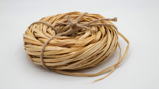 Round bundle of natural dried straw or raffia tied with jute twine on a white background