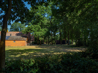 Obraz premium Beautiful rural backyard with brick barn building under high green trees on a sunny summer day 