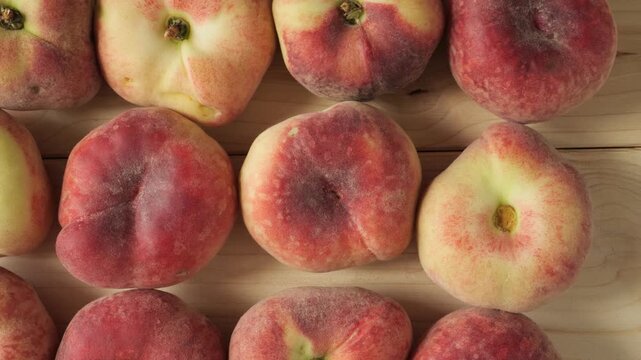 Ripe flat peaches on a wooden surface