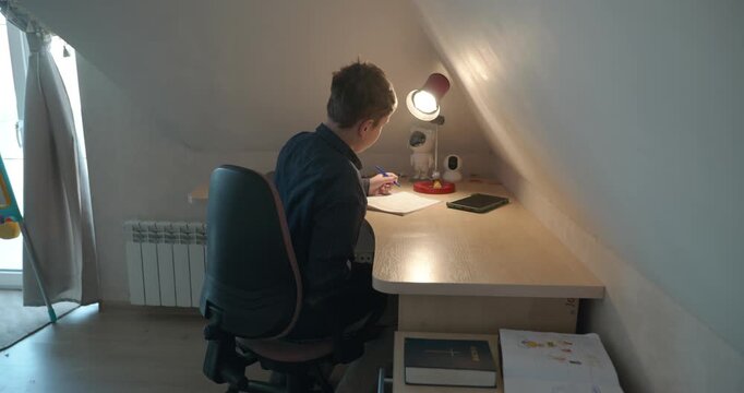 Kid Boy Doing Homework in Workbook Writing with Pen on Table Desk. 4K 10-bit