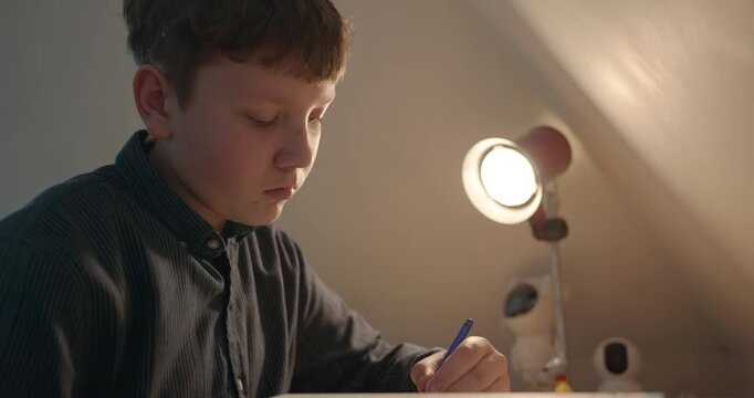 Kid Boy Doing Homework in Workbook Writing with Pen on Table Desk. 4K 10-bit