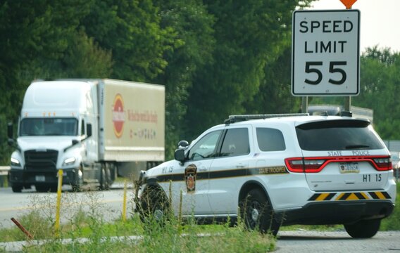 Pennsylvania, U.S.A - Jul 17, 2026 - A State Trooper SUV parked roadside monitoring traffic near semi-truck and speed limit 55 sign.