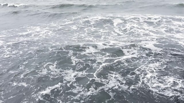 Powerful Ocean Waves Crashing on Sandy Beach Coastline Under Blue Summer Sky with Sea Foam and Natural Seascape Motion