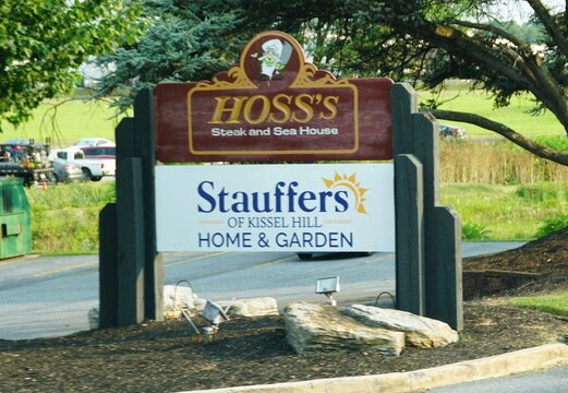 Mechanicsburg, Pennsylvania, U.S.A - Jul 17, 2026 - A road sign displaying Hoss''s Steak and Sea House and Stauffers of Kissel Hill Home and Garden
