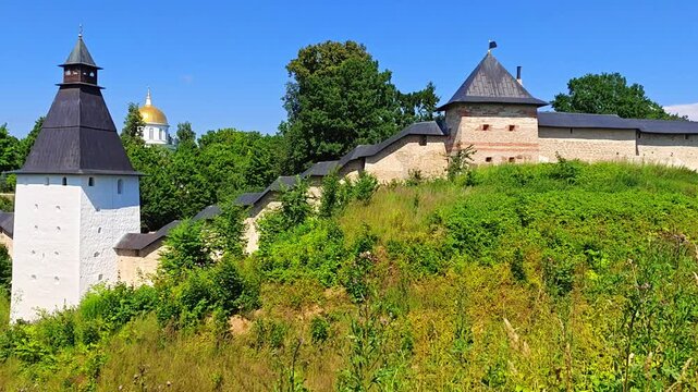 The walls and tower of the ancient Pskov-Pechersky Monastery and a view of St. Michael's Cathedral. Pechory, Russia