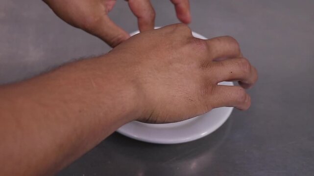 Preparaci&oacute;n de sopa de tortilla con tiras de tortilla frita. Manos colocando tortilla crujiente para sopa tradicional mexicana. Tiras de tortilla frita en plato hondo blanco. Tortilla frita lista.