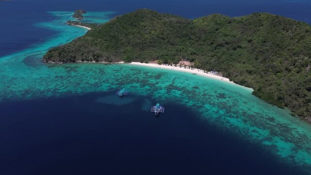 Aerial perspective of a lush green tropical island with a white sand beach and clear turquoise sea