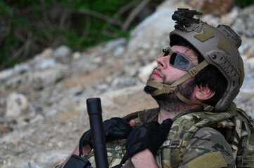 Obraz premium Focused military infantry soldier lying prone on rugged rocky terrain aiming a tactical assault rifle during a dangerous combat training mission for national defense and special security.