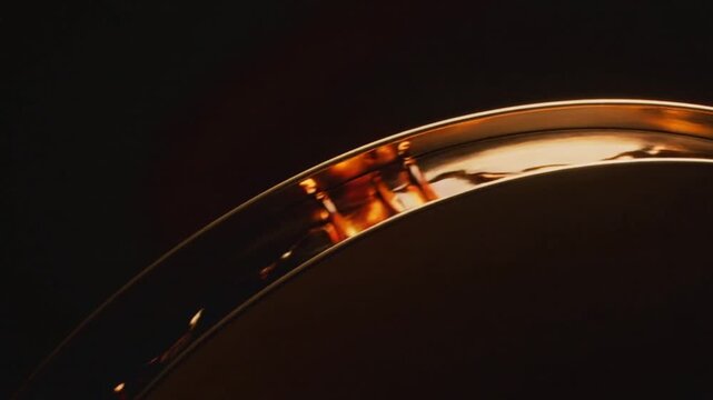 Panning camera revealing curved channel on polished disc, exposing amber liquid streaks and bokeh