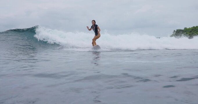 Surfer girl riding on surfboard during surfing. Female surfer rides on ocean wave