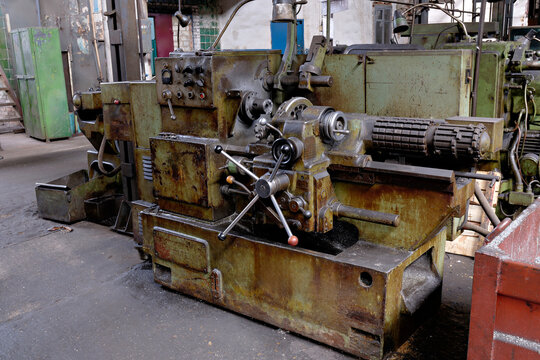 Old vintage metalworking lathe machine and industrial equipment inside heavy industry factory workshop setting.