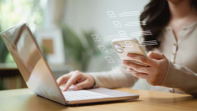 Business professional using a smartphone and laptop to complete a digital checklist, supporting task management, workflow, planning and productivity.