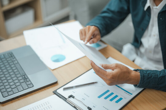 Business professional reviewing corporate financial reports, charts and planning documents for analysis and strategic decisions.