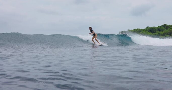 Surfer riding on surfboard during surfing. Female surfer rides on ocean wave